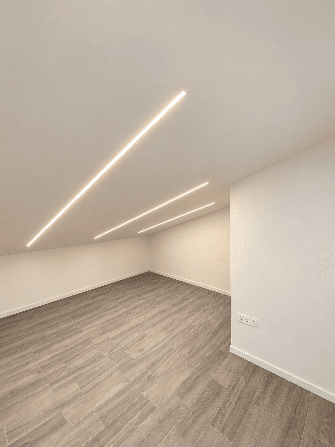 Estancia abuhardillada terminada, con paredes lisas y tiras LED integradas en el techo